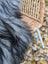 A plush, long-haired gray and black faux fur throw draped over a woven wicker chair.