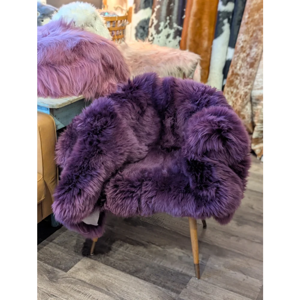 Purple sheepskin area rug with wooden legs, 68x35 inches