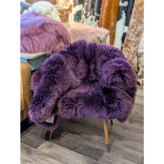 Purple sheepskin area rug with wooden legs, 68x35 inches