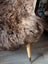 A plush curly brown british isles sheepskin throw draped over a chair leg arriving soon