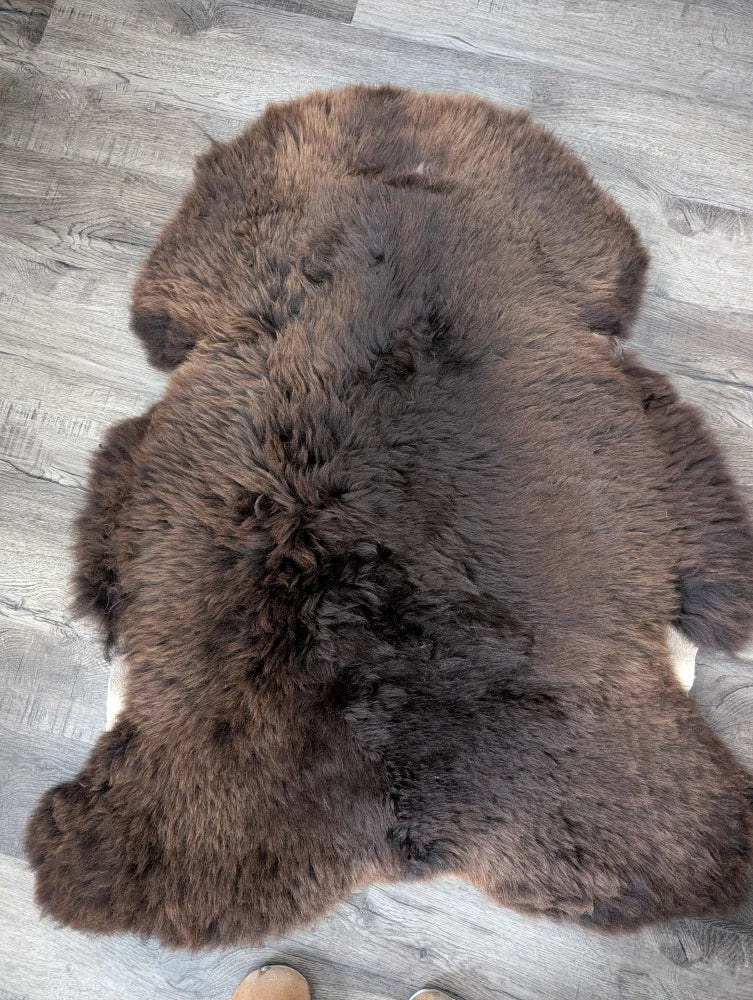 A plush dark brown british isles sheepskin rug with natural shape and dense soft fur arriving soon