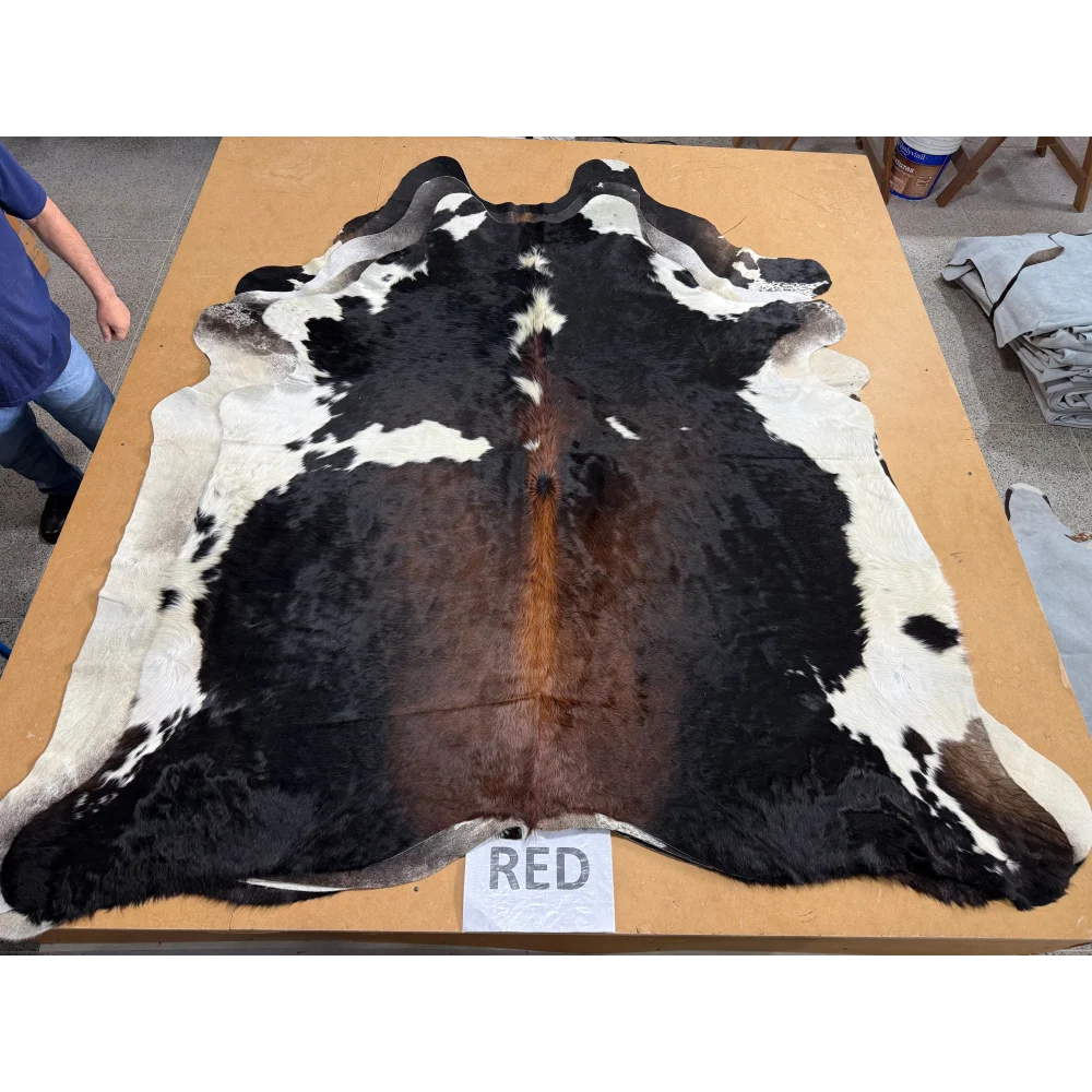 Extra large cowhide rug with black white brown patches on wooden table