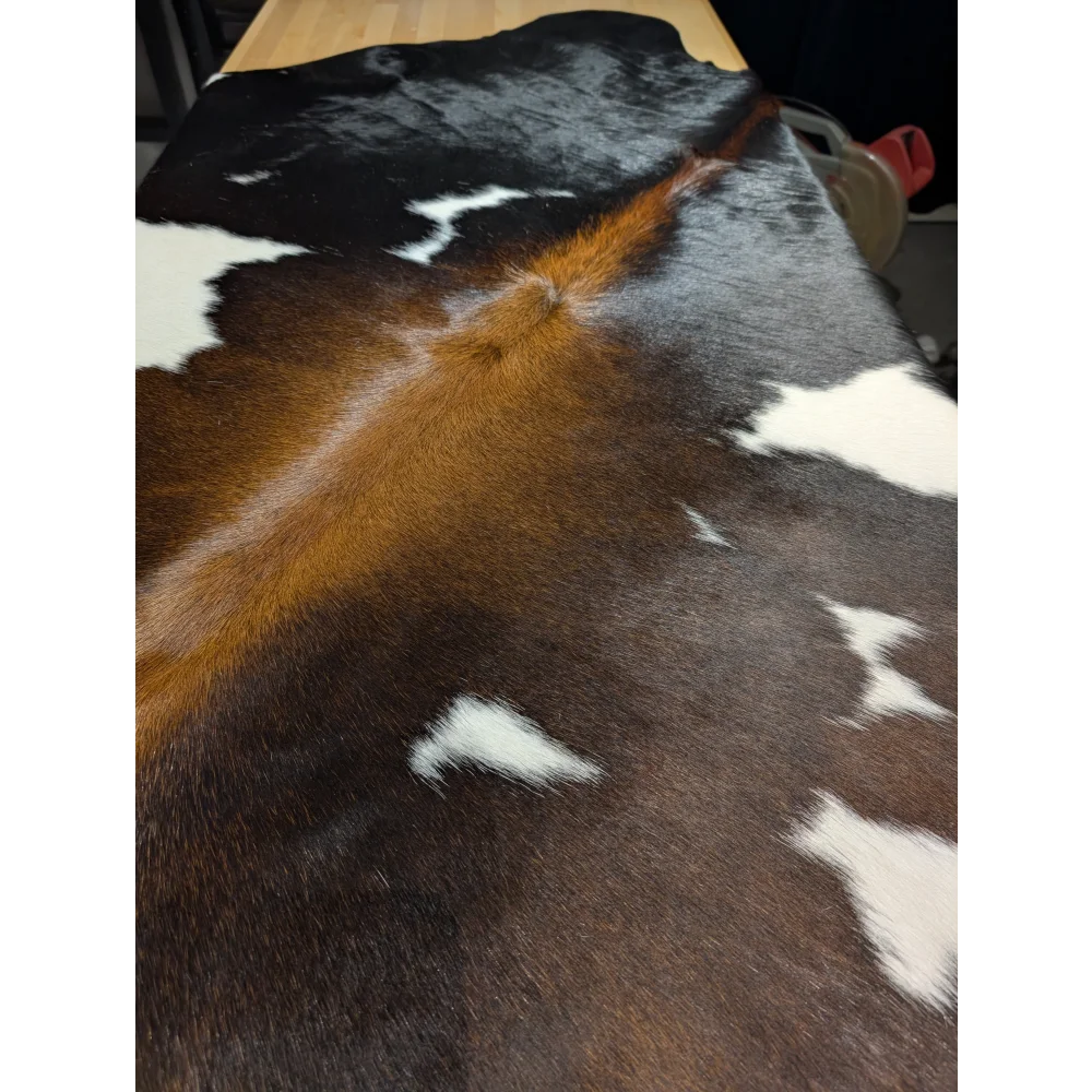Extra large cowhide rug with brown, black, white patches on wood