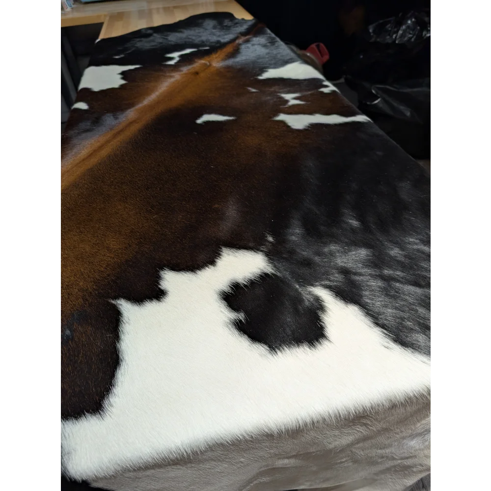 Extra large cowhide rug with brown black white patches on wood