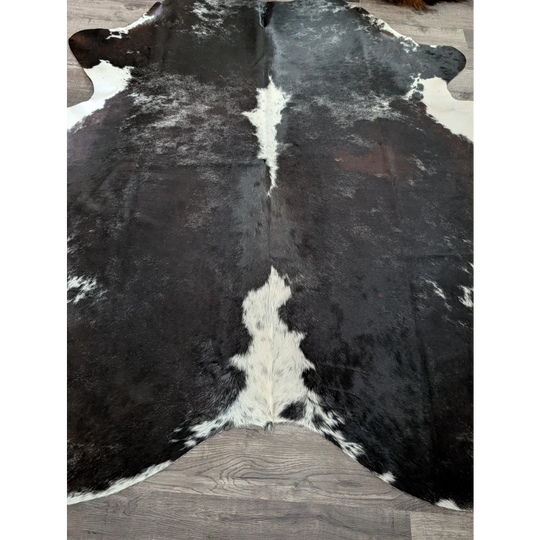 Extra large black and white cowhide rug with natural irregular patches in a reddish 89 by 77 large cowhide design