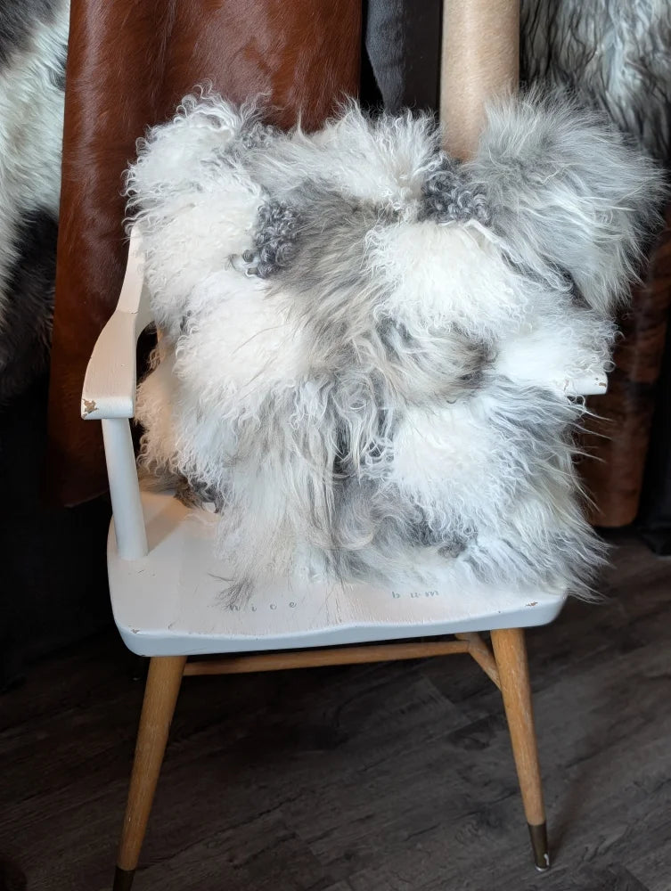 Grey sheepskin cushion throw draped on white wooden chair
