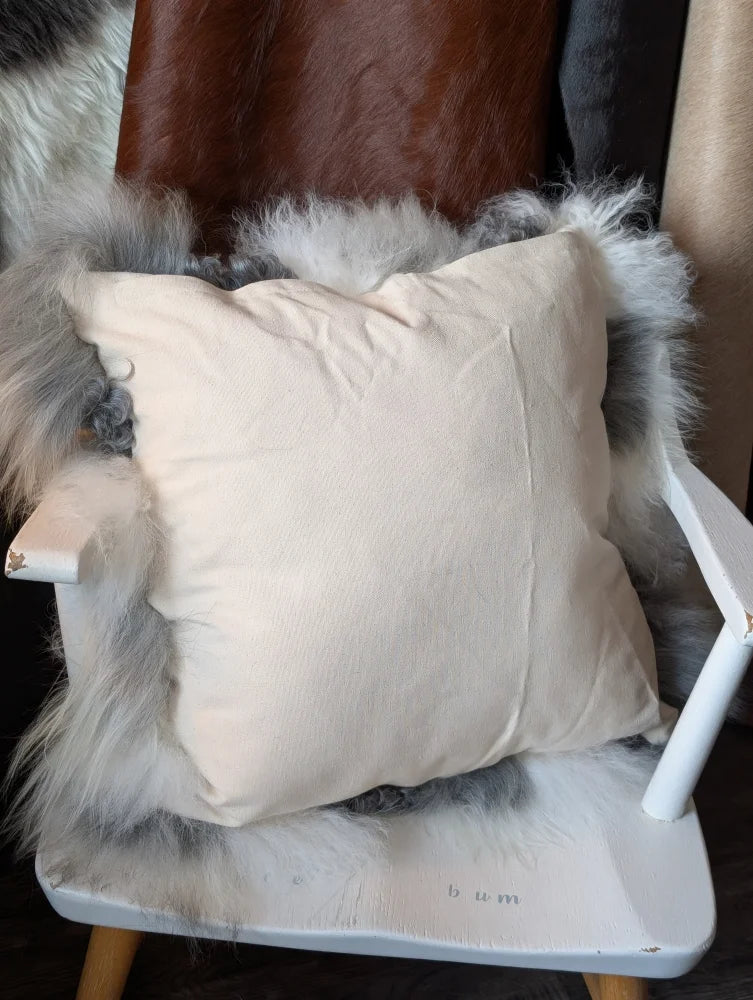 Cream-colored grey sheepskin cushion on white wooden chair