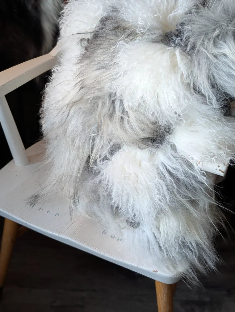 Fluffy grey sheepskin cushion draped over chair