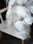 Fluffy grey sheepskin cushion draped over chair