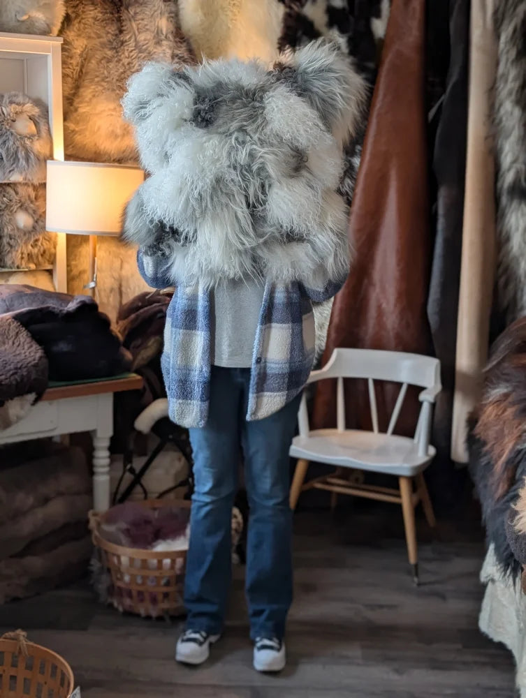 Fluffy grey sheepskin cushion vest over checkered plaid shirt
