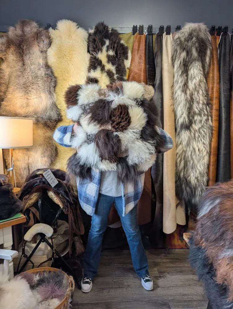 Person in plaid shirt holds ridiculously over the top checkered sheepskin cushion