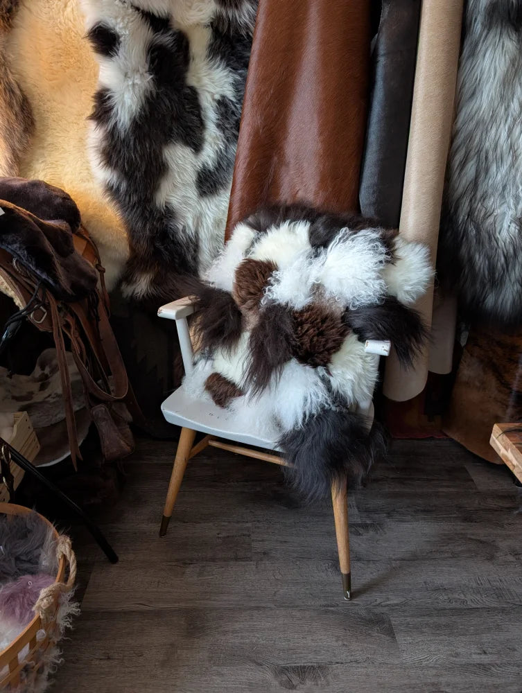 Cozy white chair with checkered sheepskin cushion and plush fur blanket