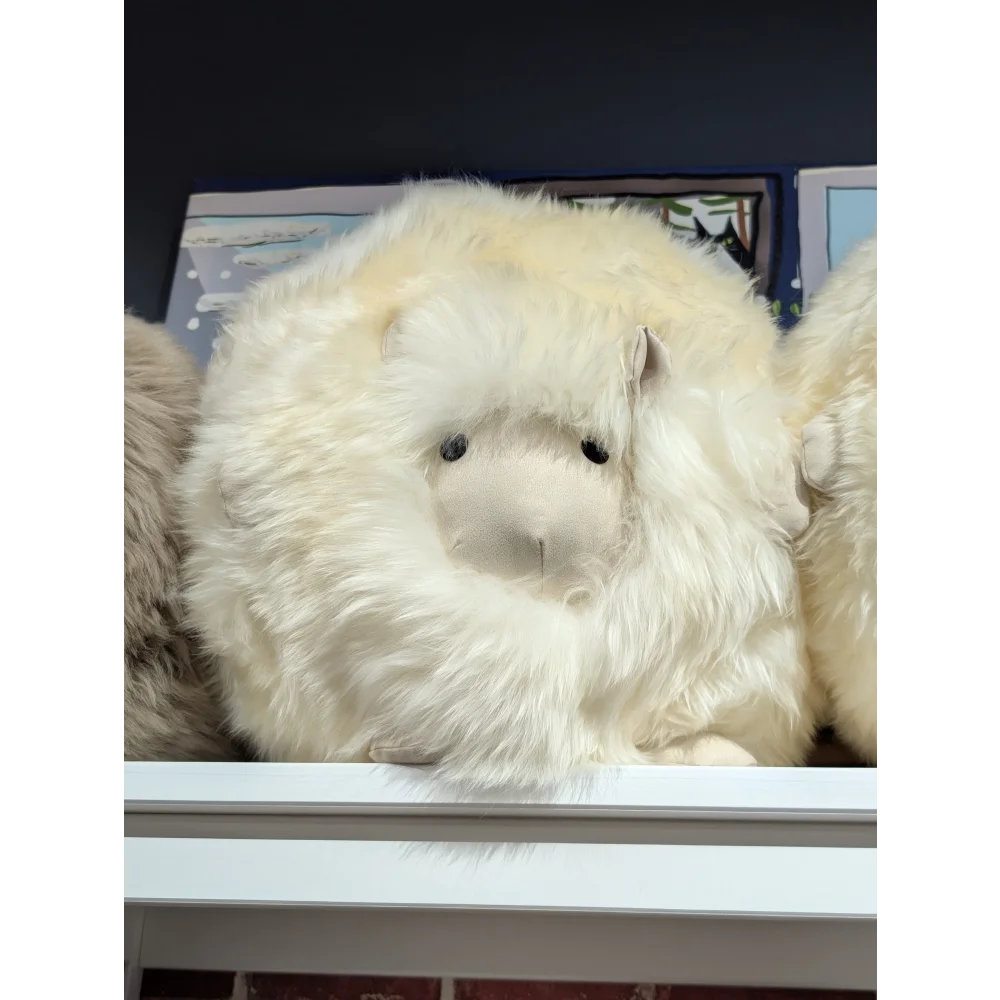 Cream-colored plush sheepskin cushion, like a Build-A-Bear stuffed animal