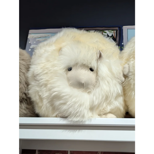 Cream-colored plush sheepskin cushion, like a Build-A-Bear stuffed animal