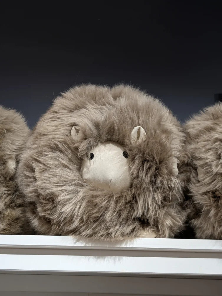 Plush Jellycat sheep toy on sheepskin cushion