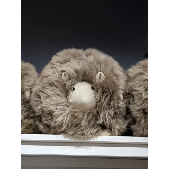 Plush Jellycat sheep toy on sheepskin cushion