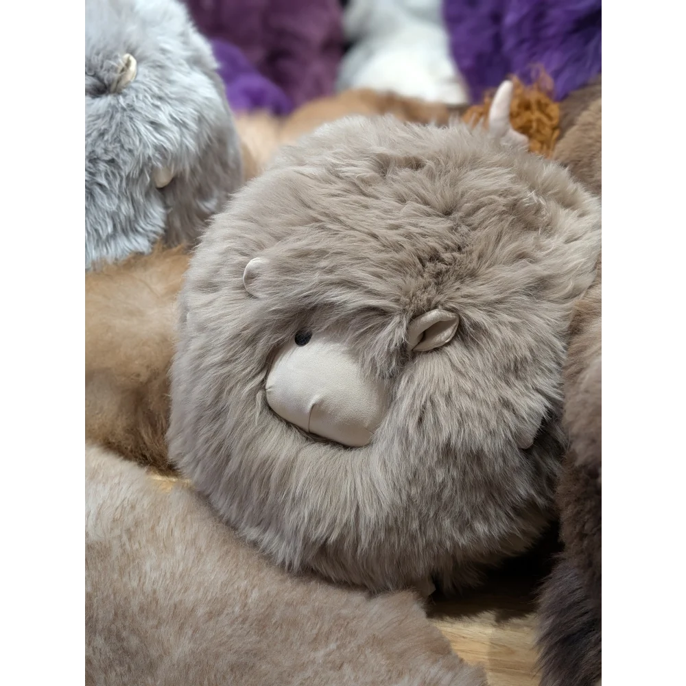 Cute gray plush sheepskin cushion with closed eyes and smile