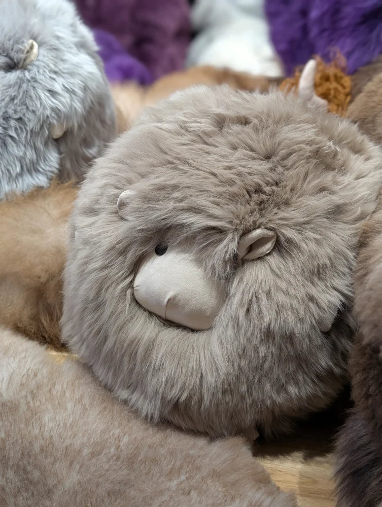 Cute gray plush sheepskin cushion with closed eyes and smile