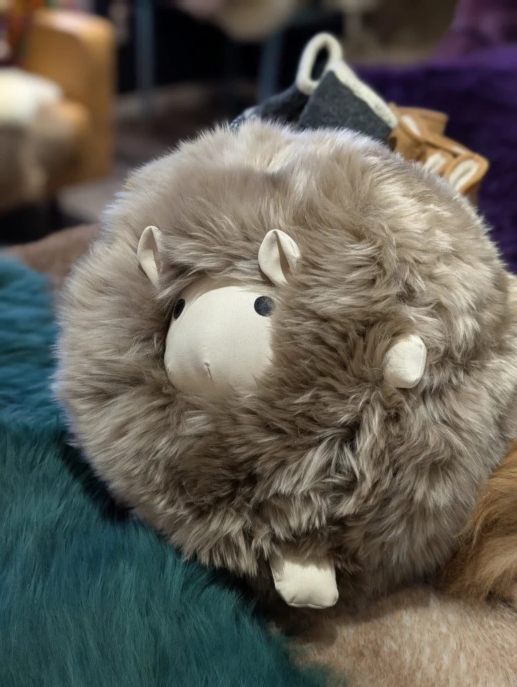 Cute gray plush sheep toy with white face, horns, like a Gotland sheepskin cushion