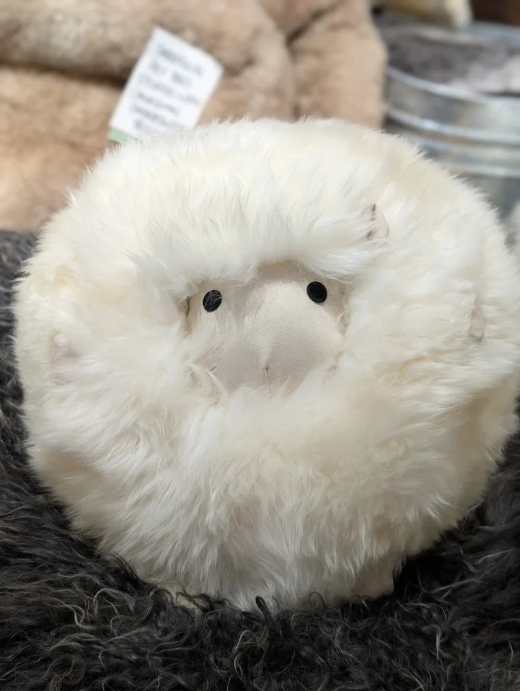Cream-colored plush owl toy on Gotland sheepskin cushion