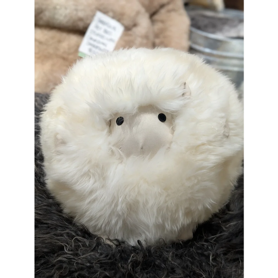 Cream-colored plush owl toy on Gotland sheepskin cushion