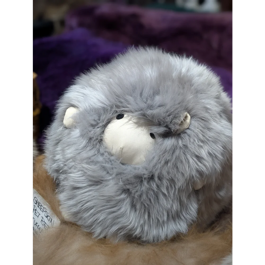 Grey fluffy guinea pig plush on Gotland sheepskin cushion