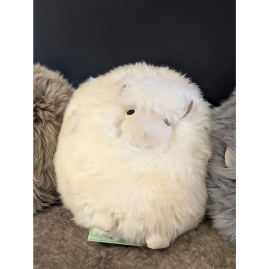 Cute white plush bunny on soft Icelandic sheepskin cushion