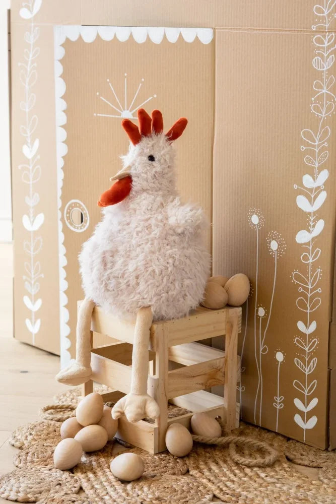 Fluffy white plush chicken roy the rooster with red comb and beak sitting on a wooden stool