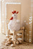 Fluffy white plush chicken roy the rooster with red comb and beak sitting on a wooden stool