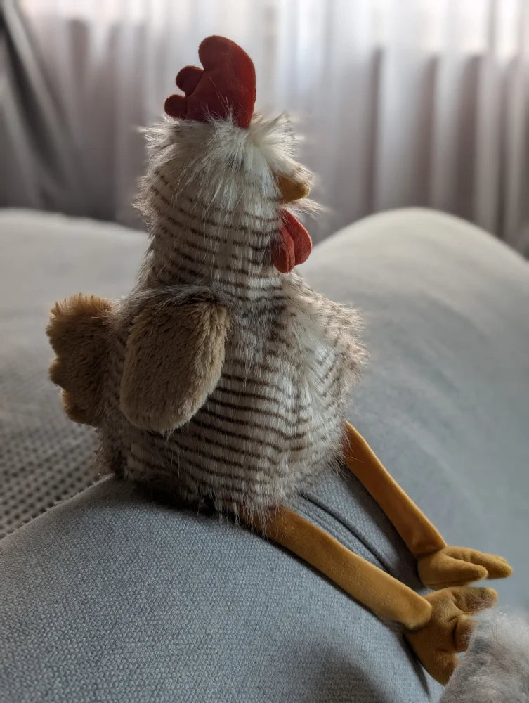 A plush chicken toy named rupert the rooster with white gray stripes red comb and yellow feet from nana huchy