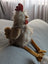 A plush chicken toy named rupert the rooster with white gray stripes red comb and yellow feet from nana huchy