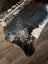 Salt and pepper brown extra large cowhide rug with natural fur texture and black and white spots on wooden floor