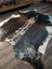 A beautiful extra large salt and pepper brown cowhide rug with a speckled black and white pattern on wooden floor