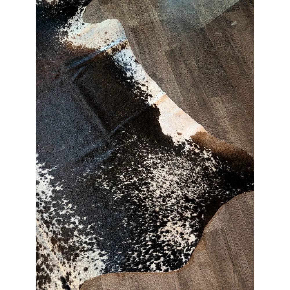 A beautiful extra large black and white speckled cowhide rug salt and pepper brown 91 x 76 on wooden floor
