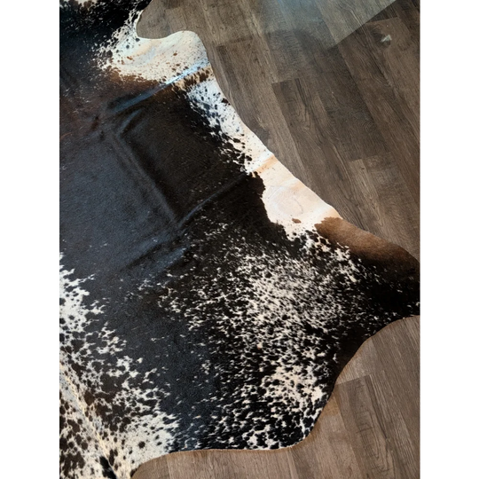 A beautiful extra large black and white speckled cowhide rug salt and pepper brown 91 x 76 on wooden floor
