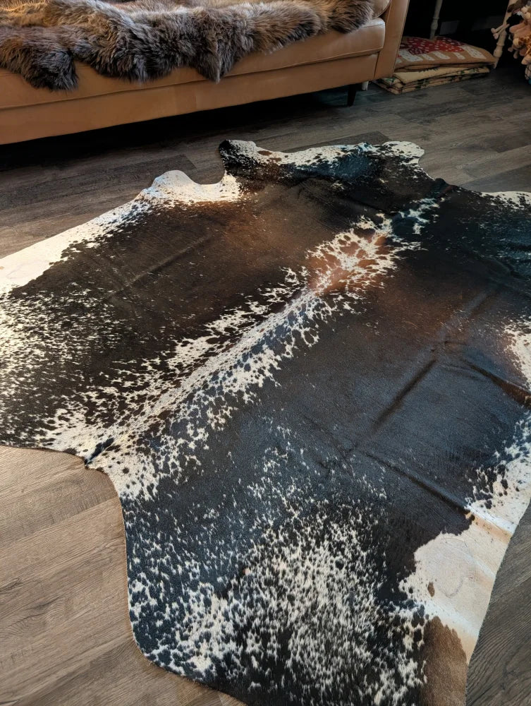 A beautiful extra large cowhide rug with a striking black and white spotted salt and pepper brown pattern