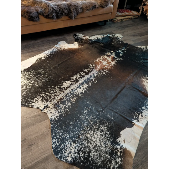 A beautiful extra large cowhide rug with a striking black and white spotted salt and pepper brown pattern