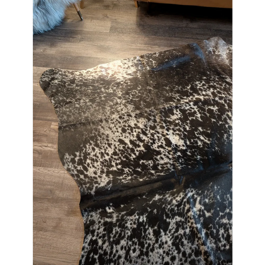 A beautiful extra large cowhide rug in salt and pepper tri color with black and white speckles and natural edges