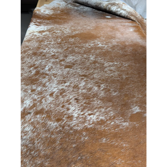 Extra large cowhide rug with brown leather wallet chain, white speckles, textured surface, unmistakable aura