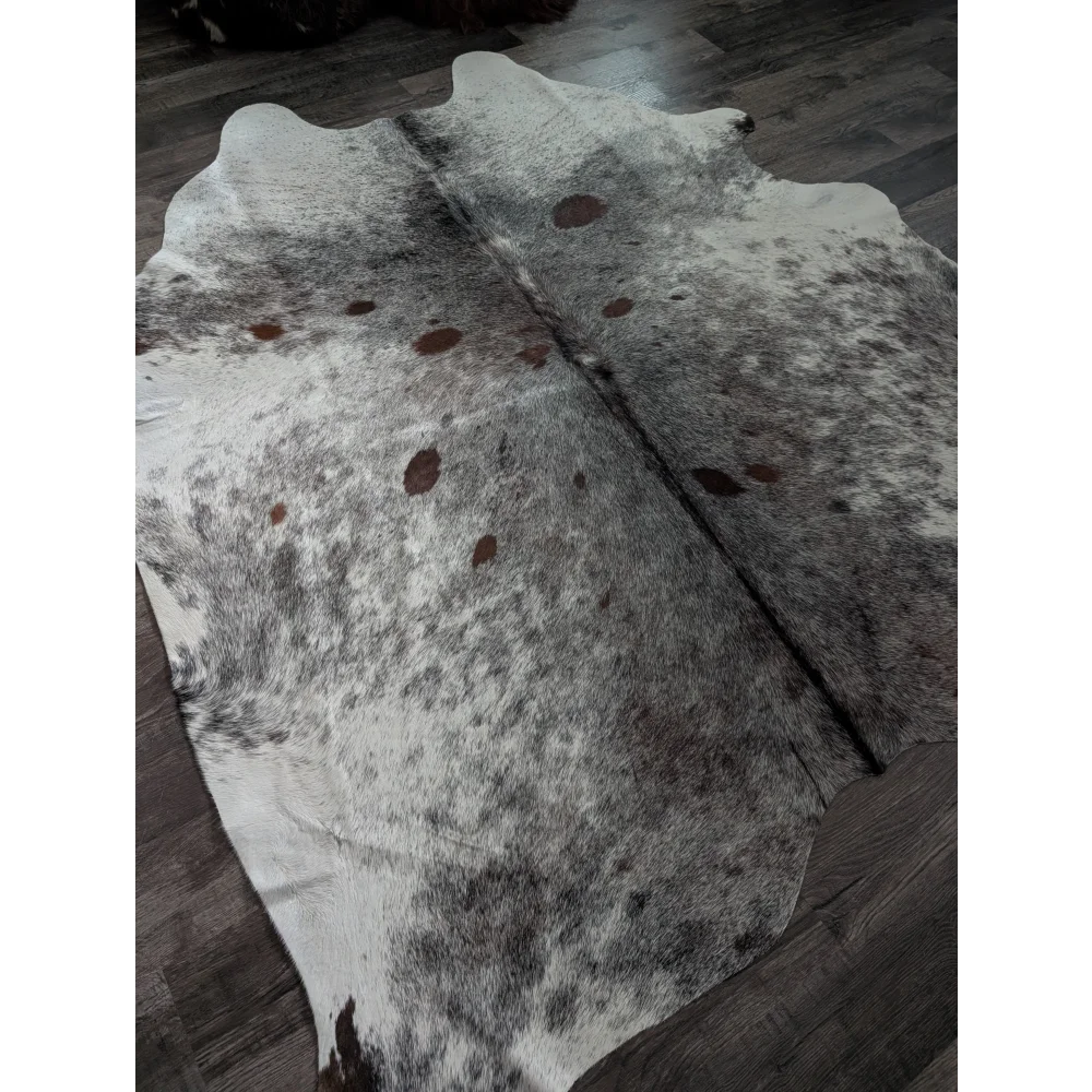 Extra large natural white and brown spotted cowhide rug laid flat on dark wood floor perfect large cowhide option