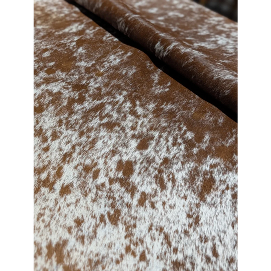 Brown and white speckled cowhide wallet chain on extra large cowhide rug