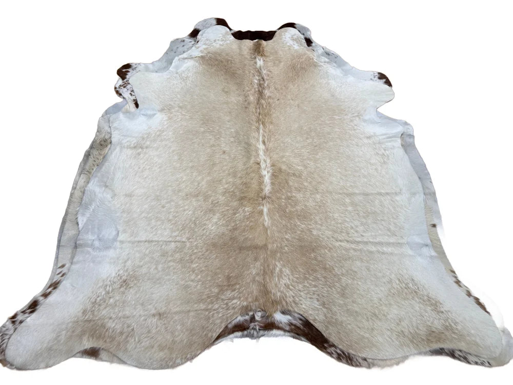 A large cowhide rug saltpepbrn#327 with soft beige white fur and dark brown patches adding rustic charm arriving soon