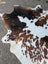 Brown and white large cowhide rug with rustic charm featuring natural dark brown patches by Angus Oliver arriving soon