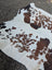 Brown and black spotted large cowhide rug with rustic charm and natural textured surface by angus oliver arriving soon