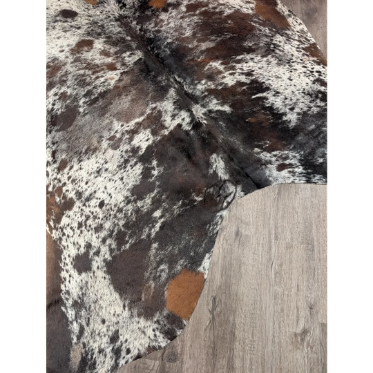 A rustic brown and white extra large cowhide rug saltpepbrn38 with a natural textured surface measuring 96 by 83 inches