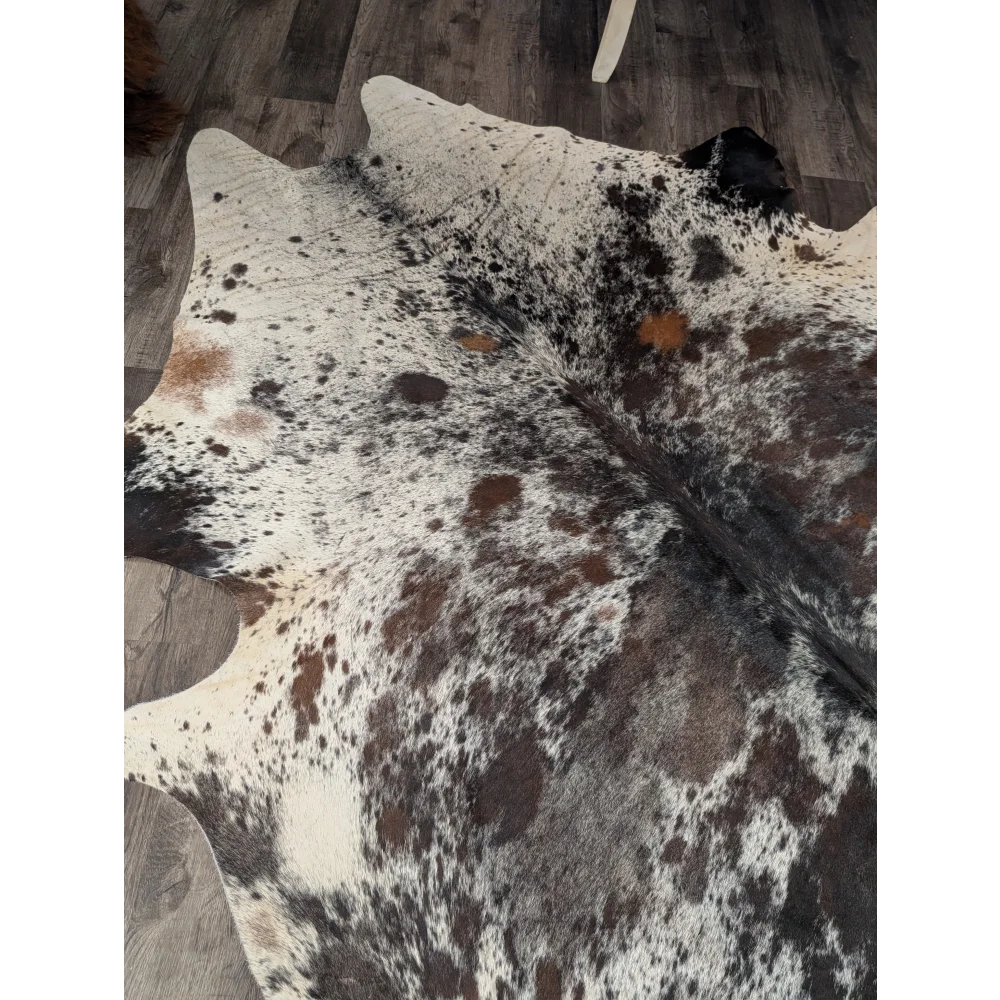 Extra large cowhide rug saltpepbrown 38 with white base and irregular black brown and tan patches measuring 96 by 83 inches