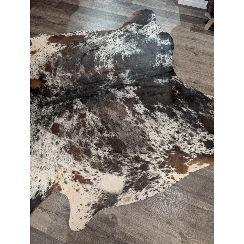 A large cowhide rug with a distinctive white black and brown patch pattern extra large saltpepbrn38 96 x 83