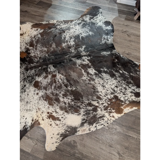 A large cowhide rug with a distinctive white black and brown patch pattern extra large saltpepbrn38 96 x 83