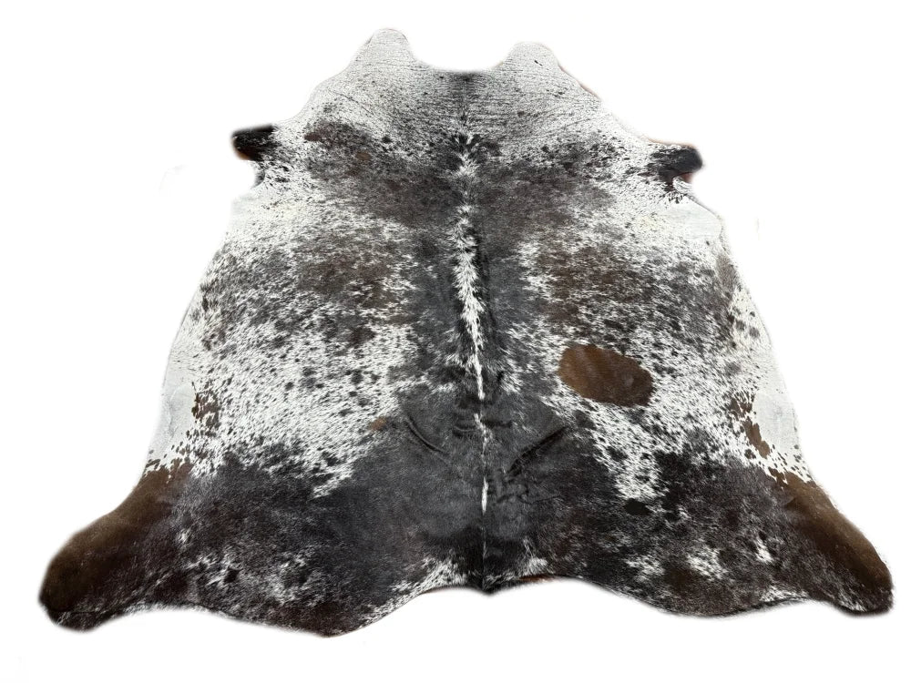 A large cowhide rug with a striking black and white spotted pattern and brown patches near edges from saltpepbrn506