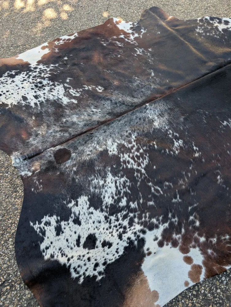 Large brown and white spotted cowhide rug with natural leather texture and unique rustic charm